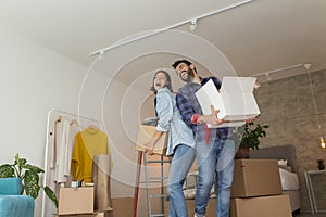 Couple carrying cardboard boxes with their possessions while moving in together photo
