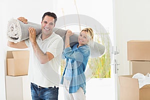 Couple carrying rolled rug after moving in a house
