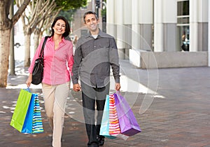 Couple Carrying Shopping Bags On City Street