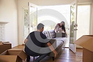 Couple Carrying Sofa Into New Home On Moving Day