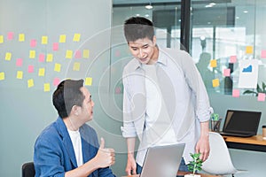 Couple of casual business men workers in modern office ,manager or boss praising thumb upto the staff