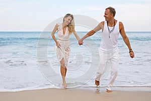 Couple in casual summer clothes having fun in ocean water