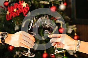 Couple celebrating by drinking red wine, she and him, clinking wine glasses, elegant dining background. Celebrate Christmas and