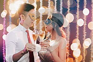 Couple celebrating New Year and drinking champagne on masquerade party