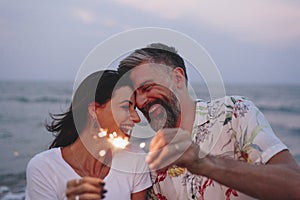 Couple celebrating with sparklers at the beach photo