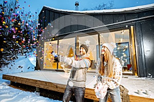 Couple celebrating winter holidays in front of the house outdoors