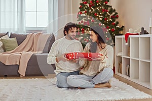 Couple Celebration New Year Near Christmas Tree at Home, Exchange Presents in the Gift Boxes