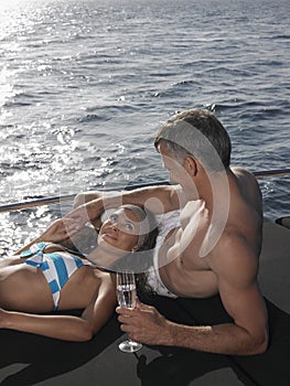 Couple With Champagne Flute Relaxing On Yacht