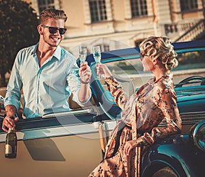Couple with champagne near classic car