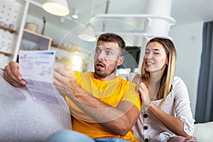 Couple checking bank account trouble sitting on a couch in the living room at home