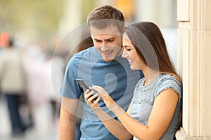 Couple checking content in a smart phone on the street