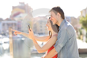 Couple checking phone pointing away on vacation