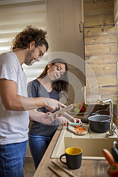 Couple checking recipe using tablet computer while cooking lunch