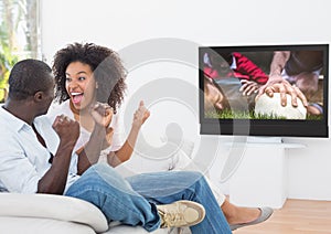 Couple cheering while watching rugby match on television