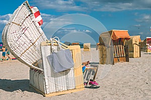 Couple chill relax in striped roofed chairs on sandy beach in Travemunde., Lubeck, Germany