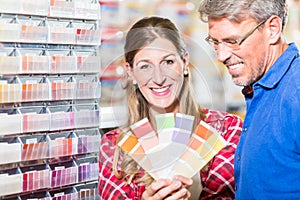 Couple choosing color of paint in hardware store