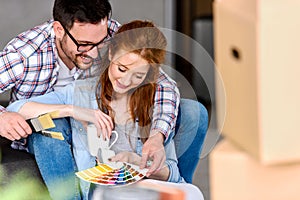 Couple choosing colors for painting home; having fun