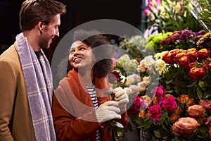 Couple Choosing Flowers From Florist Stall At Outdoor Christmas Market