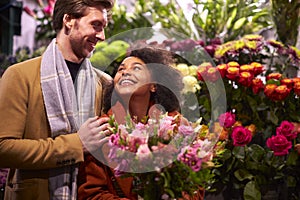 Couple Choosing Flowers From Florist Stall At Outdoor Christmas Market