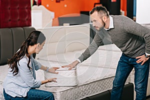 couple choosing folding mattress together in furniture store photo