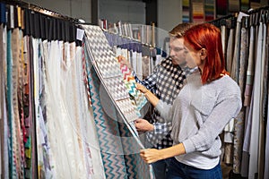 Couple choosing textile at home decoration store, shop. Making of home interior design during quarantine