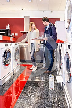 Couple Choosing Washing Machine In Hypermarket photo