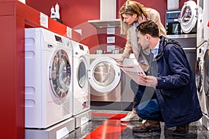 Couple Choosing Washing Machine At Hypermarket photo