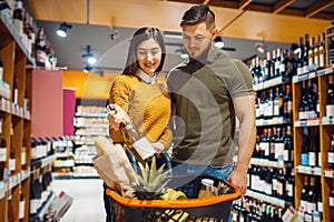 Couple choosing wine in grocery supermarket