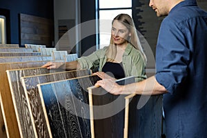 Couple choosing wood texture laminate floor from samples in flooring store for house improvements