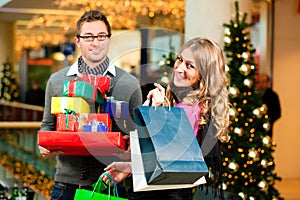 Couple with Christmas presents and bags in mall