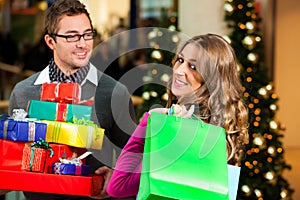 Couple with Christmas presents and bags in shoppin