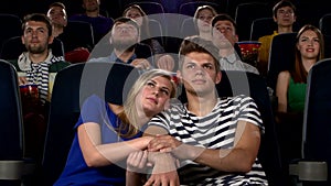 Couple in cinema watching a movie, and kissing