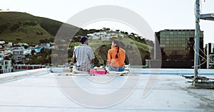 Couple, city rooftop and relax together with love, friendship and romance during a sunset picnic. Urban friends, freedom