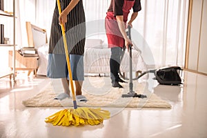 Couple clean bedroom by mop, vacuum cleaner