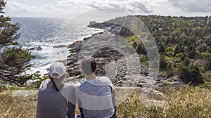 Couple on a cliff looking at the rocky coastline in Maine United States