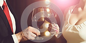 Couple clink glasses with red wine at meeting or wedding