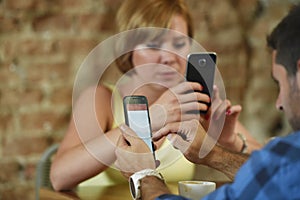 Couple at coffee shop with man and woman using mobile phone networking ignoring each other