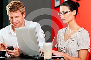 Couple in coffeeshop with laptop and mobile photo
