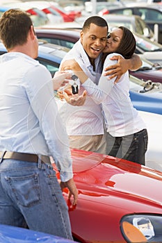 Couple collecting new car from salesman