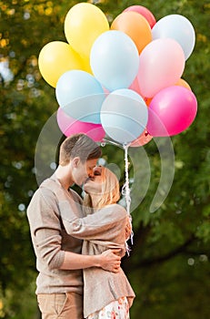 Couple with colorful balloons kissing in the park