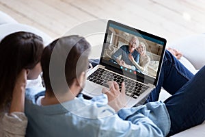 Couple communicating with elderly parents using laptop and videocall app photo