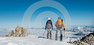 Couple connected team rope  with climbing harness dressed mountaineering clothes with backpacks and ice axes enjoying views