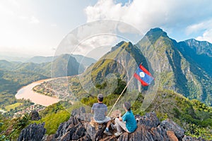 Couple conquering mountain top at Nong Khiaw panoramic view over Nam Ou River valley Laos national flag scenic mountain landscape