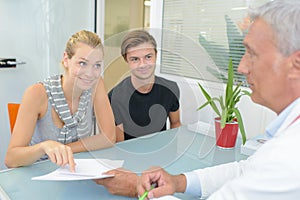 Couple in consultation with doctor looking hopeful