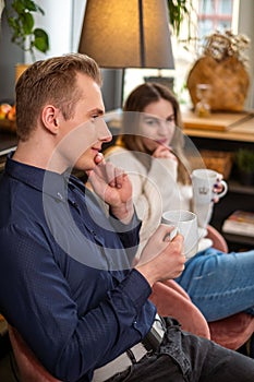 Couple in contemplative coffee break, man in blue shirt introspective, woman in white, a scene of serene domesticity and