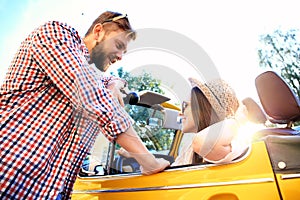 Couple in convertible. Beautiful young couple enjoying road trip in convertible and looking at each other with smile