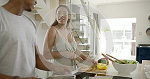 Couple cooking, preparing a meal and having fun together while bonding, dancing and laughing in a home kitchen. Smiling