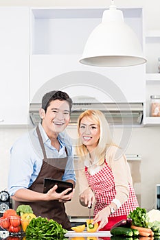 Couple cooking after recipes from tablet computer