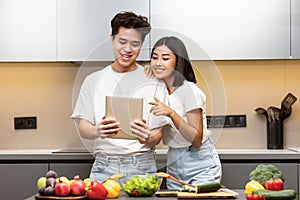 Couple Cooking Using Digital Tablet Searching Recipe Online In Kitchen