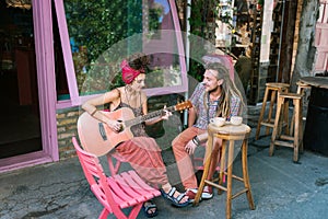 Couple of creative hippies drinking tea sitting on summer terrace